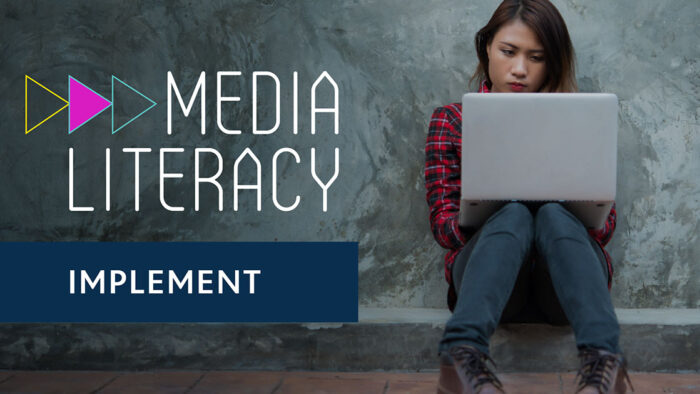 Implement Media Literacy (background shows person sitting against a wall viewing media on a laptop)