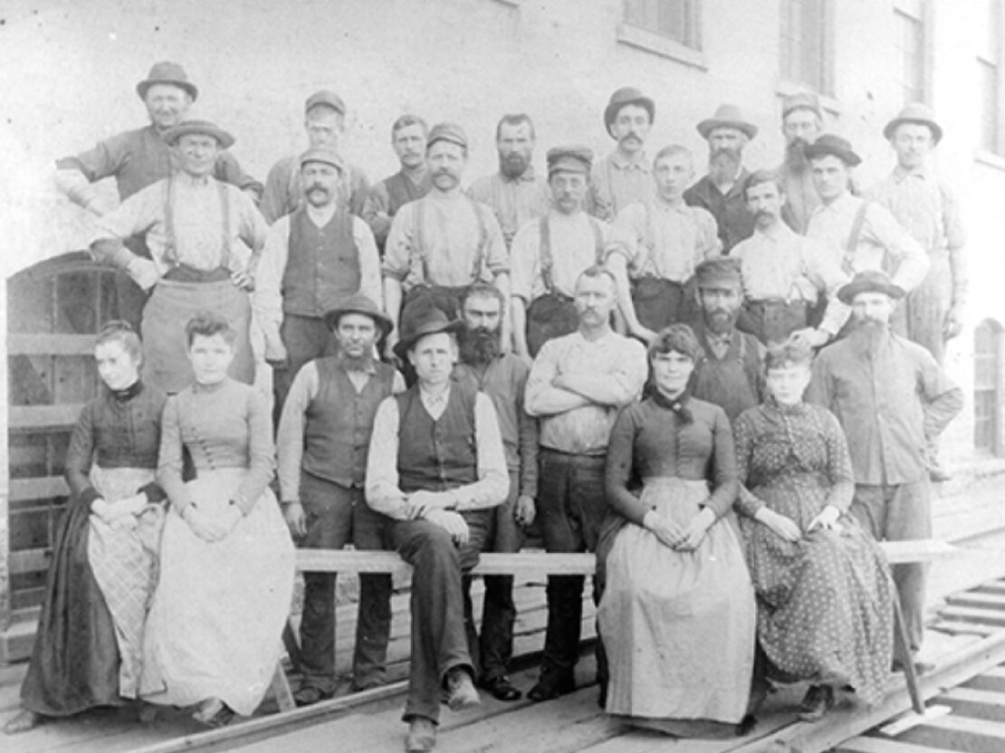 A black and white photo of a group of people, some seated and some standing, posing for a picture.