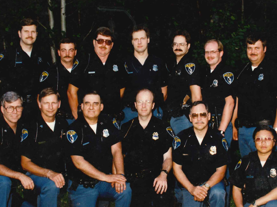A color image showing two rows of people in police uniforms posing for a photo.