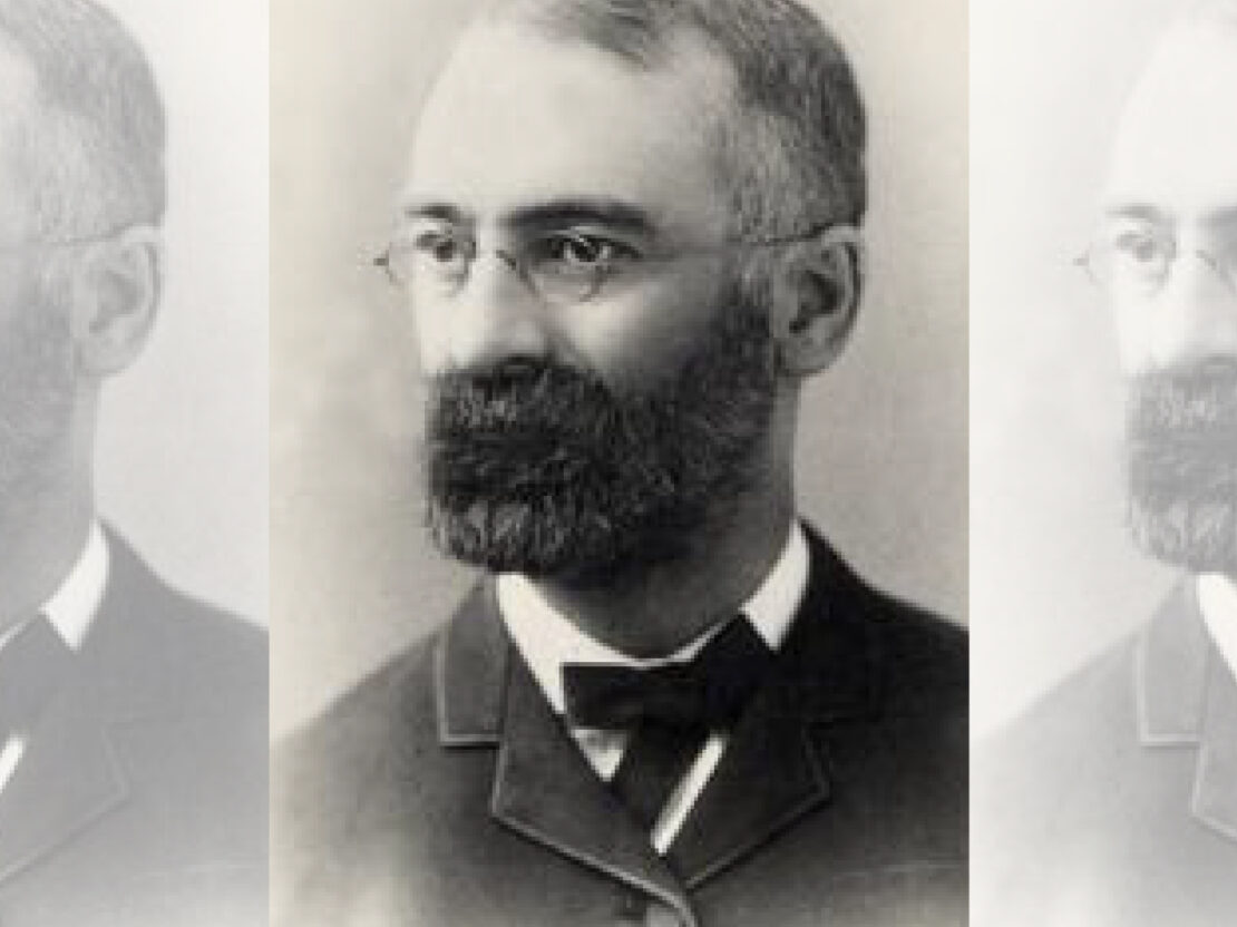 A black and white portrait of Stephen, in which his head and shoulders are visible. He has a beard, and is wearing glasses. He is looking to the left of the viewer.